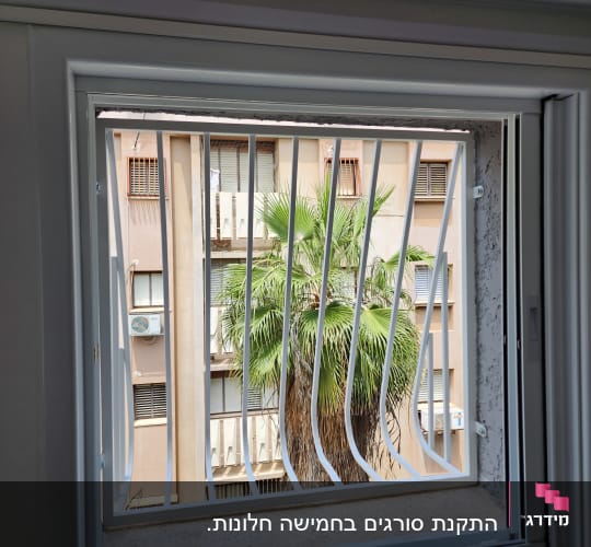 חלון עם סורגים לבנים ומסגרת לבנה